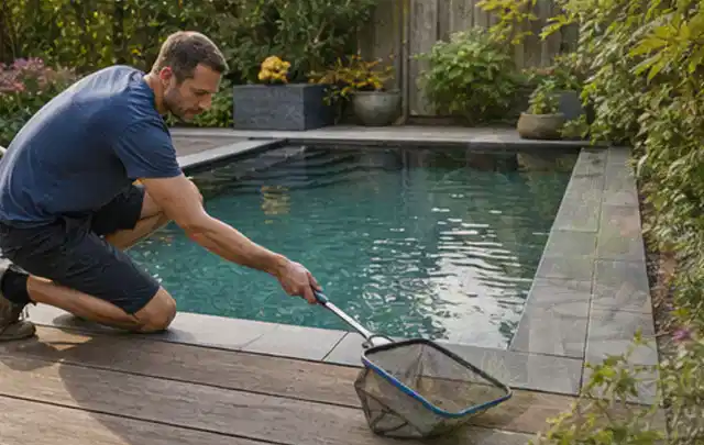 Person entfernt Blätter mit einem Kescher aus einem kleinen Gartenpool; Thema Sonnenschirme, Schwerpunkt Reparatur; Praxisalltag.