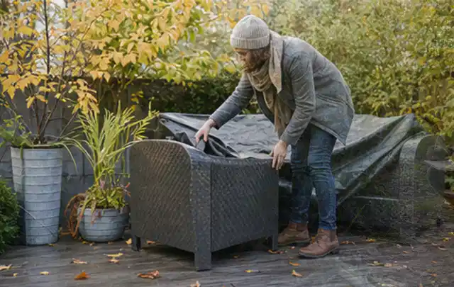Person deckt Gartenmöbel vor der kalten Jahreszeit sorgfältig ab; Thema Sonnenschirme, Schwerpunkt Vergleich; Ergebnis.