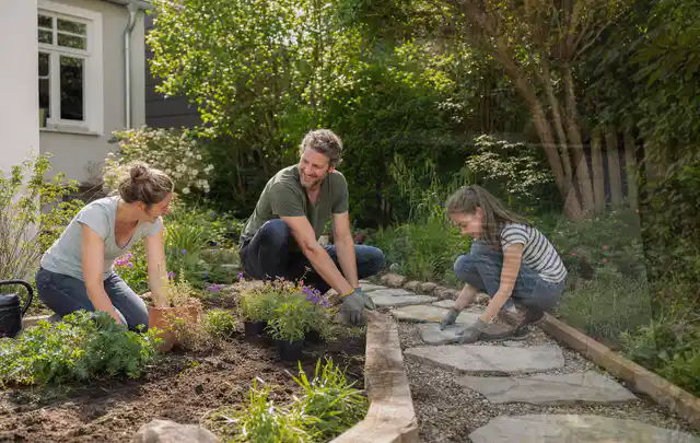 Familie geht auf einem Weg durch einen abwechslungsreich gestalteten Garten; Thema Steingarten, Schwerpunkt Gärten mit kleiner Fläche; Praxisalltag.