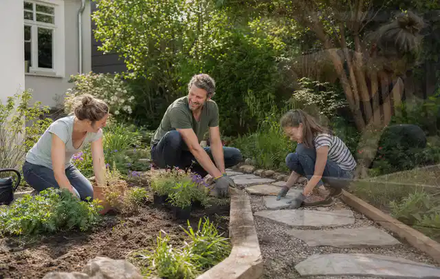 Familie geht auf einem Weg durch einen abwechslungsreich gestalteten Garten; Thema Steingarten, Schwerpunkt Hanglage; Umsetzung.