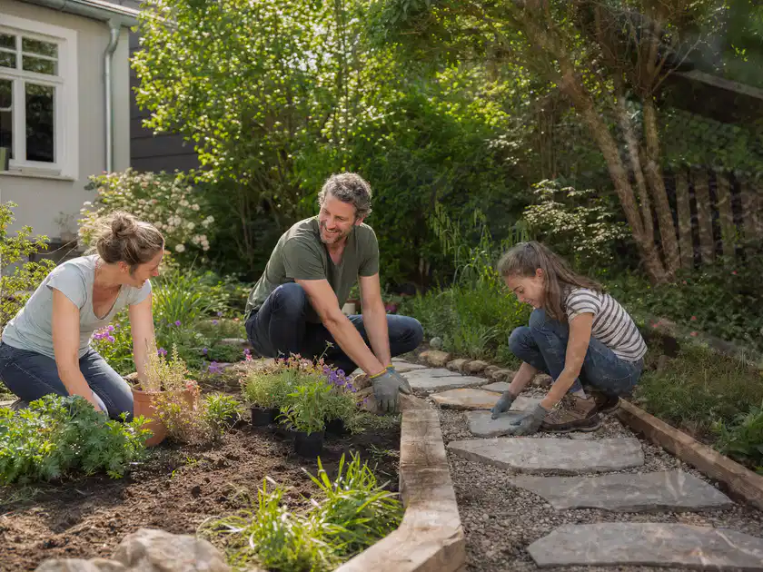 Familie geht auf einem Weg durch einen abwechslungsreich gestalteten Garten; Thema Steingarten, Schwerpunkt Inspiration; Titelbild.