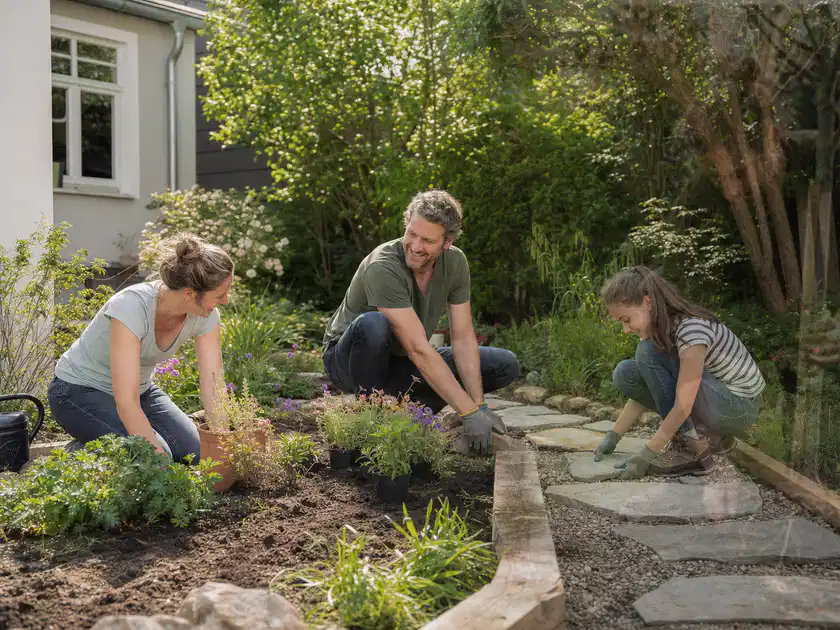 Familie geht auf einem Weg durch einen abwechslungsreich gestalteten Garten; Thema Steingarten, Schwerpunkt Materialwahl; Titelbild.