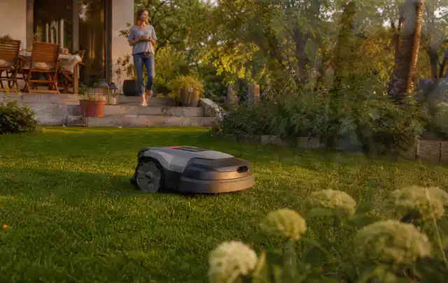 Mähroboter fährt am Abend über einen Rasen im Familiengarten; Thema Stihl iMow, Schwerpunkt Fehlerhilfe; Umsetzung.