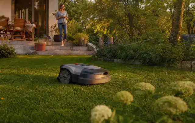 Mähroboter fährt am Abend über einen Rasen im Familiengarten; Thema Stihl iMow, Schwerpunkt Nachhaltigkeit; Kontrolle.