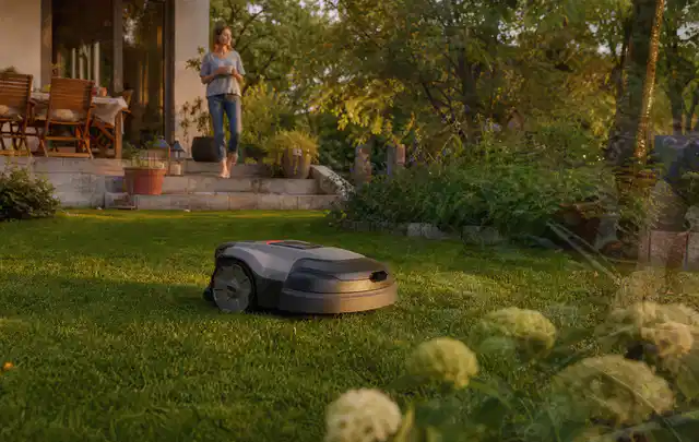 Mähroboter fährt am Abend über einen Rasen im Familiengarten; Thema Stihl iMow, Schwerpunkt Reinigung; Umsetzung.