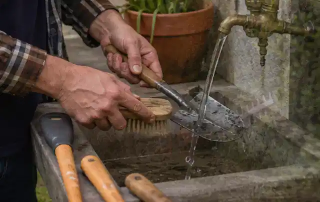 Hände reinigen gebrauchte Gartengeräte mit Bürste und Wasser am Außenbecken; Thema Stihl iMow, Schwerpunkt Vergleich; Kontrolle.