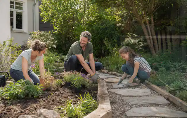 Familie geht auf einem Weg durch einen abwechslungsreich gestalteten Garten; Thema Terrasse, Schwerpunkt Garten gestalten; Umsetzung.