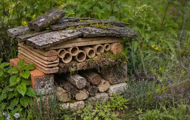 Naturnaher Unterschlupf aus Holz Rinde und Pflanzenstängeln im Garten; Thema Vorgarten, Schwerpunkt Beleuchtung; Praxisalltag.