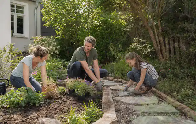 Familie geht auf einem Weg durch einen abwechslungsreich gestalteten Garten; Thema Vorgarten, Schwerpunkt Materialwahl; Ausgangslage.