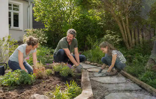 Familie geht auf einem Weg durch einen abwechslungsreich gestalteten Garten; Thema Wege, Schwerpunkt Garten gestalten; Kontrolle.