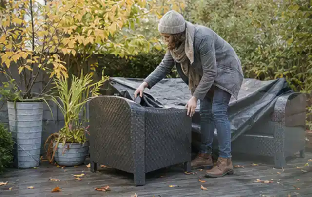 Person deckt Gartenmöbel vor der kalten Jahreszeit sorgfältig ab; Thema Whirlpools, Schwerpunkt Ersatzteile; Kontrolle.