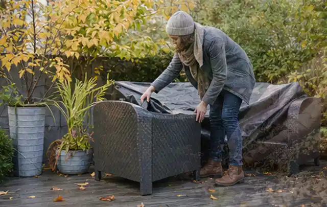 Person deckt Gartenmöbel vor der kalten Jahreszeit sorgfältig ab; Thema Whirlpools, Schwerpunkt Fehlerhilfe; Praxisalltag.
