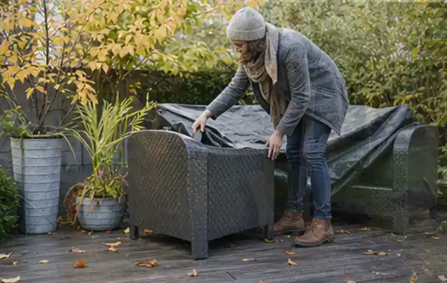 Person deckt Gartenmöbel vor der kalten Jahreszeit sorgfältig ab; Thema Whirlpools, Schwerpunkt Gärten mit kleiner Fläche; Umsetzung.