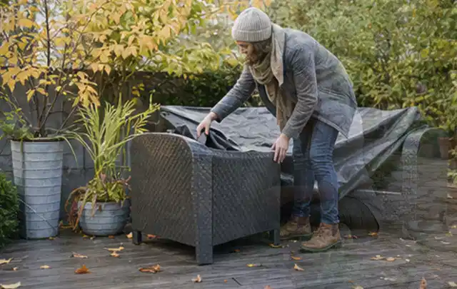 Person deckt Gartenmöbel vor der kalten Jahreszeit sorgfältig ab; Thema Whirlpools, Schwerpunkt Wartung; Umsetzung.
