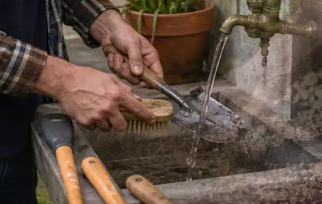 Hände reinigen gebrauchte Gartengeräte mit Bürste und Wasser am Außenbecken; Thema Worx Landroid, Schwerpunkt Anwendung; Kontrolle.