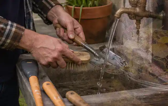 Hände reinigen gebrauchte Gartengeräte mit Bürste und Wasser am Außenbecken; Thema Worx Landroid, Schwerpunkt Gärten mit großer Fläche; Ausgangslage.