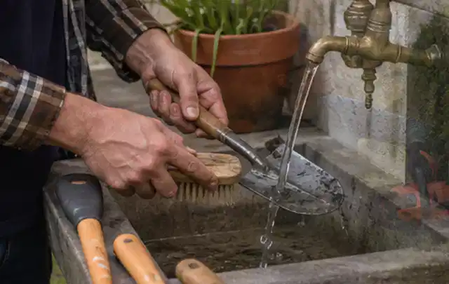 Hände reinigen gebrauchte Gartengeräte mit Bürste und Wasser am Außenbecken; Thema Worx Landroid, Schwerpunkt Reinigung; Praxisalltag.