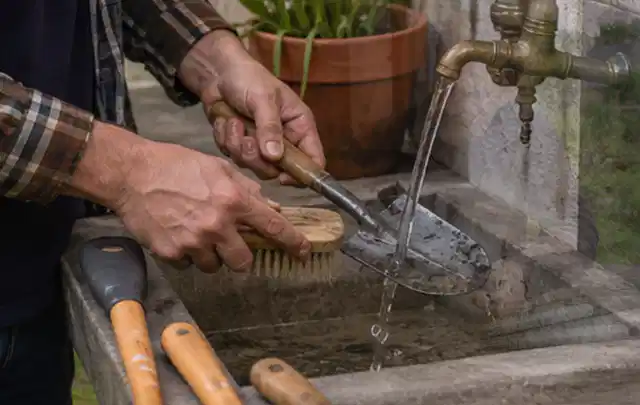 Hände reinigen gebrauchte Gartengeräte mit Bürste und Wasser am Außenbecken; Thema Worx Landroid, Schwerpunkt Reparatur; Ausgangslage.