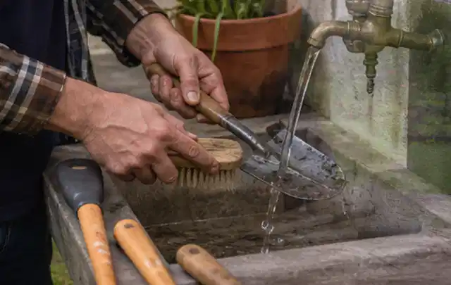 Hände reinigen gebrauchte Gartengeräte mit Bürste und Wasser am Außenbecken; Thema Worx Landroid, Schwerpunkt Vergleich; Kontrolle.