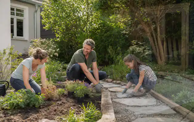 Familie geht auf einem Weg durch einen abwechslungsreich gestalteten Garten; Thema WPC Sichtschutz, Schwerpunkt Aufbau; Praxisalltag.