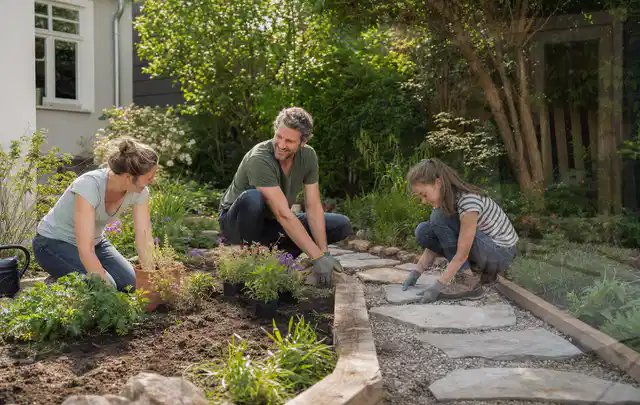Familie geht auf einem Weg durch einen abwechslungsreich gestalteten Garten; Thema WPC Sichtschutz, Schwerpunkt Kosten; Kontrolle.