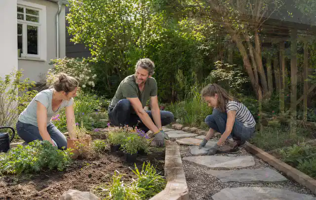 Familie geht auf einem Weg durch einen abwechslungsreich gestalteten Garten; Thema WPC Sichtschutz, Schwerpunkt Winterschutz; Ergebnis.